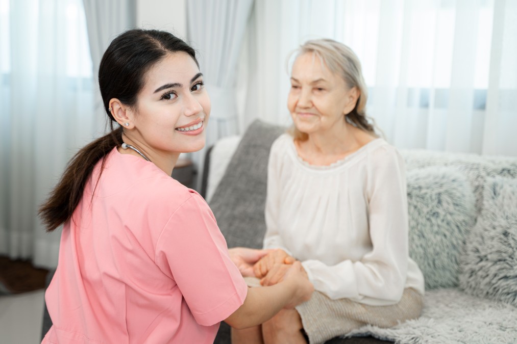 Hébergement senior : une personne âgée souriante tient la main de son accueillant familial dans un salon chaleureux.