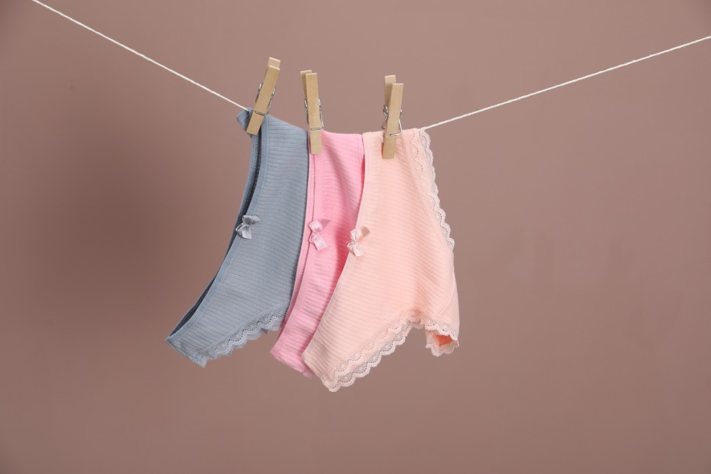 Culottes aux tons doux suspendues sur un fil avec des pinces en bois, illustrant le séchage à l'air libre indispensable après avoir bien su choisir sa culotte menstruelle.