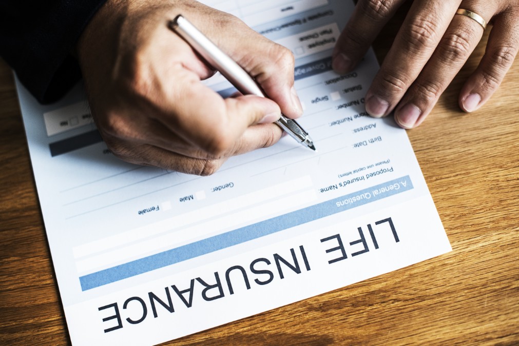 Gros plan sur la signature d'un document d'assurance pour garantir le financement des frais d'obsèques.